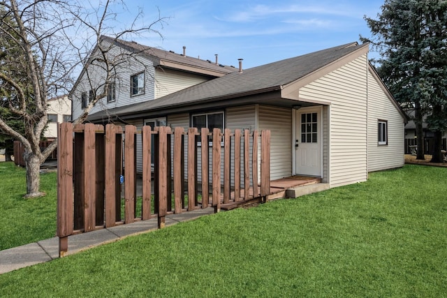 exterior space featuring a shingled roof, a front yard, and fence