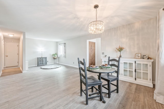 dining space with baseboards, a notable chandelier, and light wood-style flooring