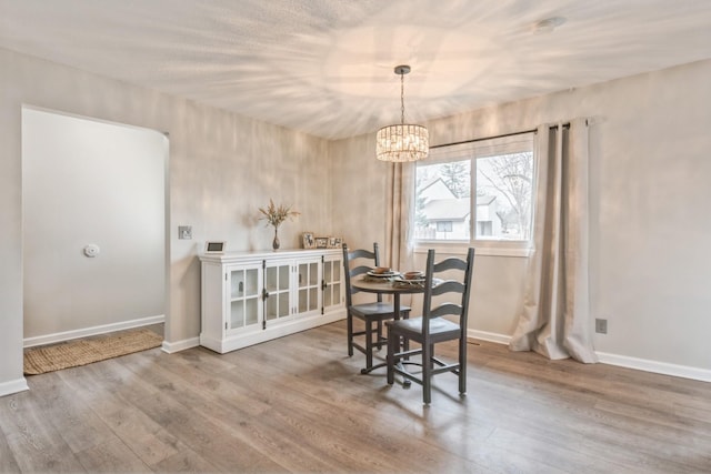 dining room with baseboards, an inviting chandelier, and wood finished floors