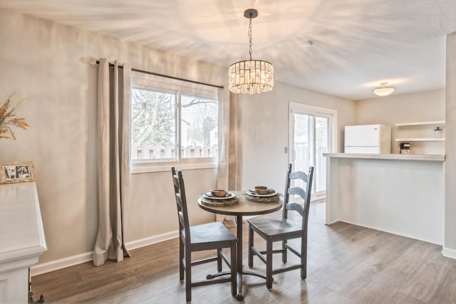 dining room with a chandelier, baseboards, and wood finished floors