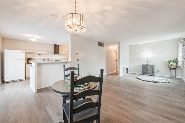 dining area with a notable chandelier, visible vents, light wood-type flooring, and baseboards