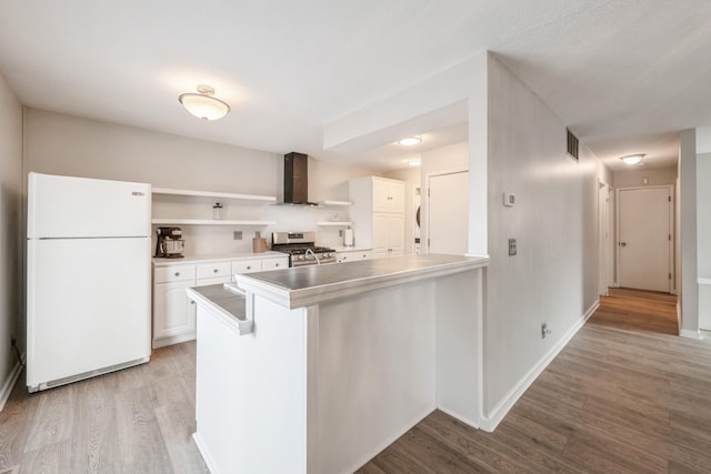 kitchen with visible vents, open shelves, freestanding refrigerator, stainless steel range with gas cooktop, and wall chimney exhaust hood