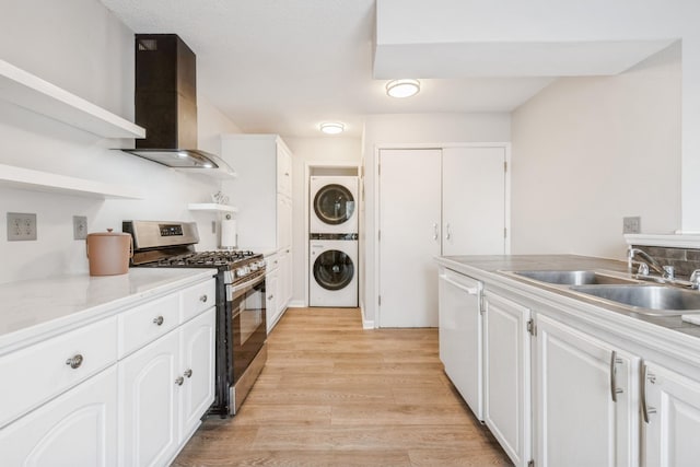 kitchen featuring stacked washer / dryer, a sink, dishwasher, wall chimney range hood, and stainless steel gas stove