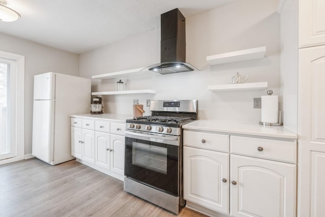 kitchen featuring range hood, open shelves, freestanding refrigerator, and stainless steel gas range