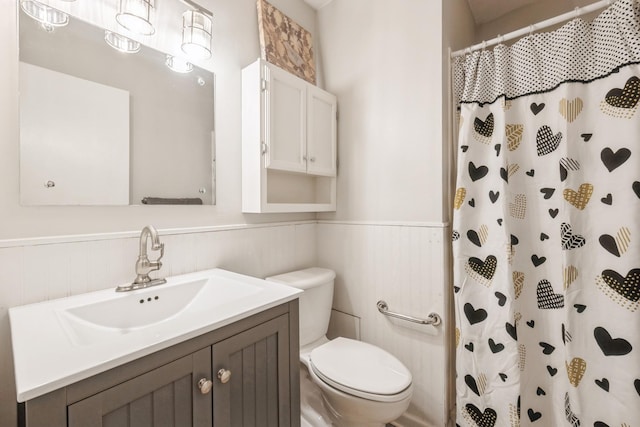 full bath with a shower with curtain, vanity, toilet, and wainscoting