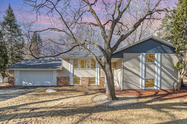 view of front of property featuring brick siding, driveway, and a garage