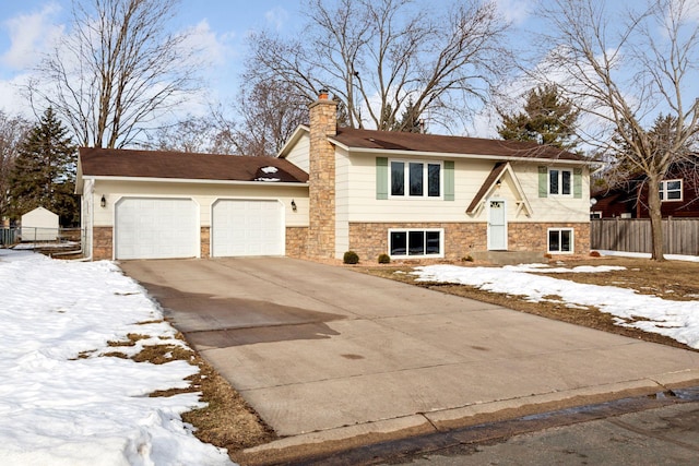 bi-level home featuring fence, a chimney, driveway, stone siding, and an attached garage