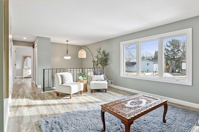 living area with visible vents, baseboards, and wood finished floors