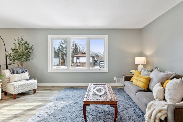 living area featuring visible vents, light wood-style flooring, and baseboards