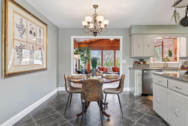 dining space featuring dark tile patterned floors, baseboards, and a chandelier