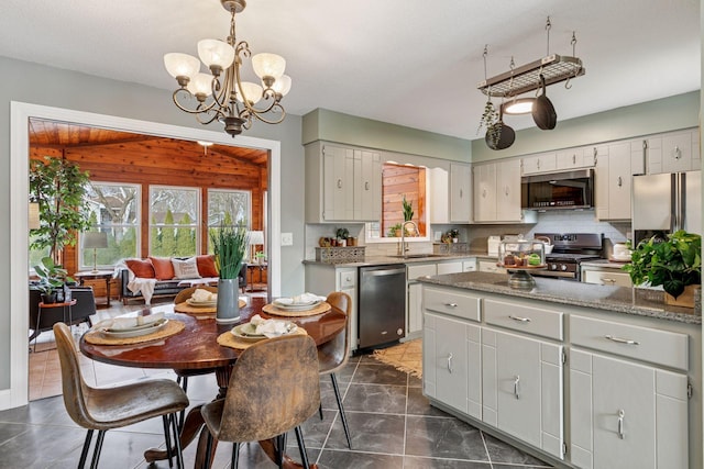 kitchen featuring tasteful backsplash, hanging light fixtures, a notable chandelier, stainless steel appliances, and a sink