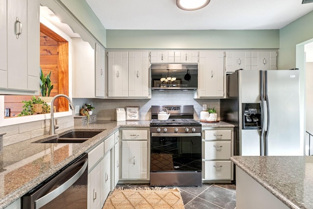 kitchen with backsplash, light stone counters, white cabinets, stainless steel appliances, and a sink