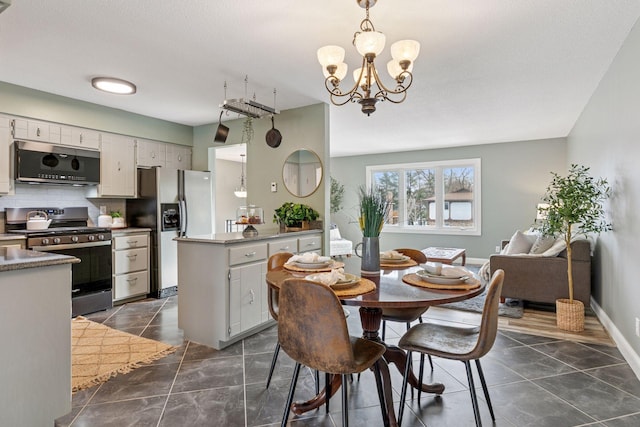 dining area featuring dark tile patterned floors, a notable chandelier, and baseboards