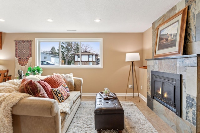 living area featuring a textured ceiling, recessed lighting, light tile patterned flooring, baseboards, and a tile fireplace