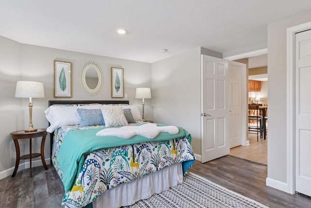 bedroom with baseboards, a textured ceiling, and wood finished floors