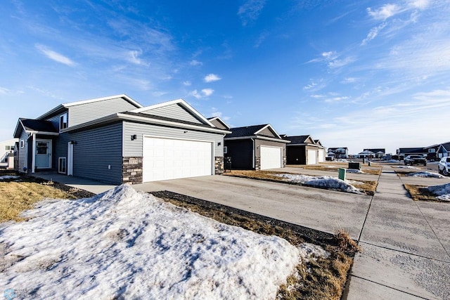 single story home featuring stone siding, driveway, and an attached garage