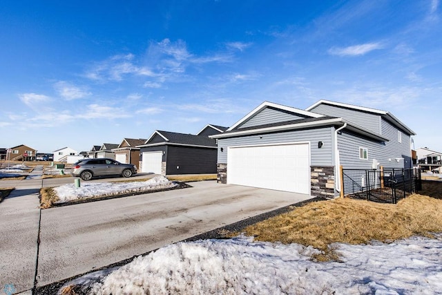 ranch-style home with a residential view, stone siding, driveway, and an attached garage