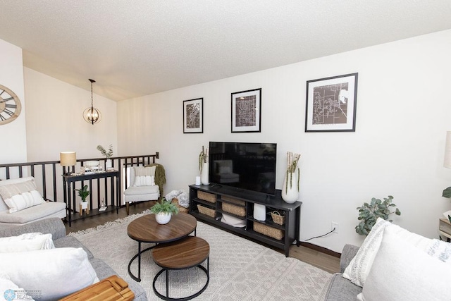 living area with vaulted ceiling, an inviting chandelier, and wood finished floors