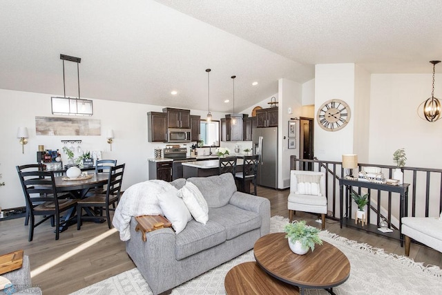 living room featuring lofted ceiling, a textured ceiling, light wood-type flooring, a chandelier, and recessed lighting