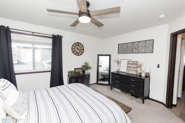 bedroom featuring light carpet, a textured ceiling, and baseboards