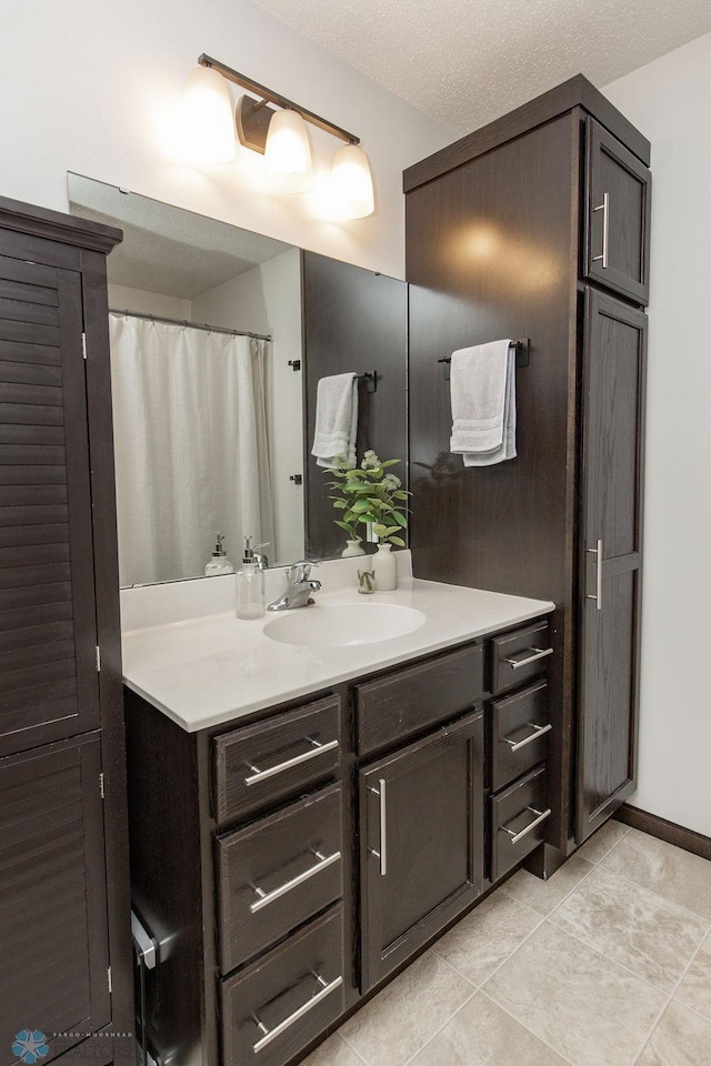 bathroom with a textured ceiling, tile patterned flooring, and vanity