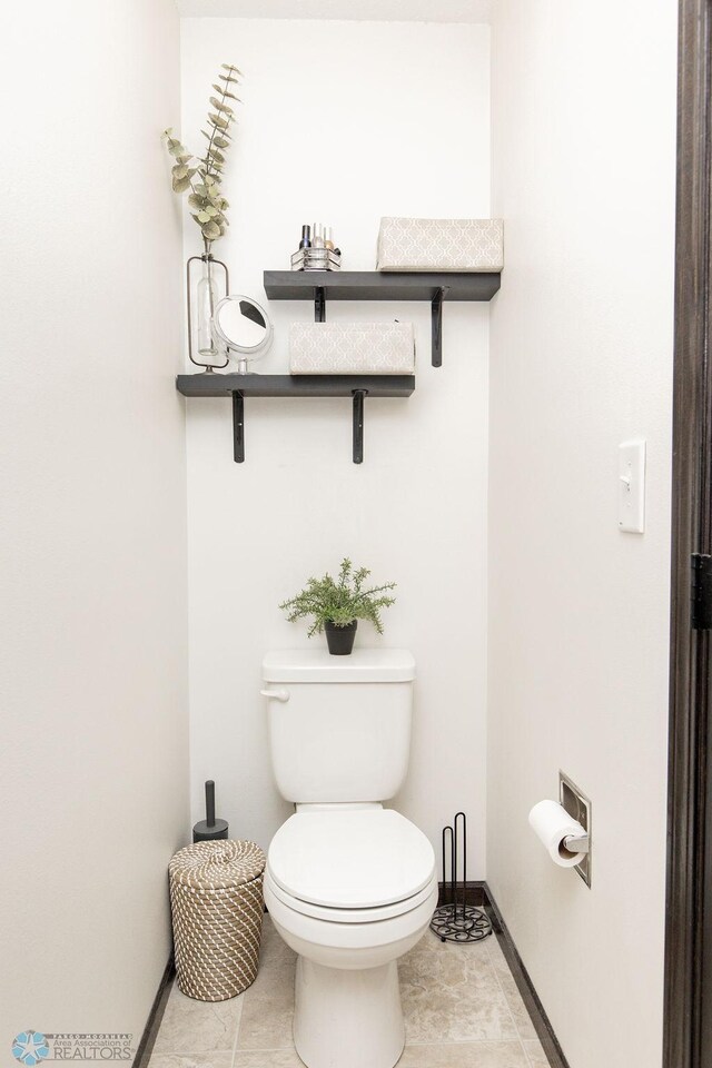 bathroom featuring toilet, tile patterned flooring, and baseboards