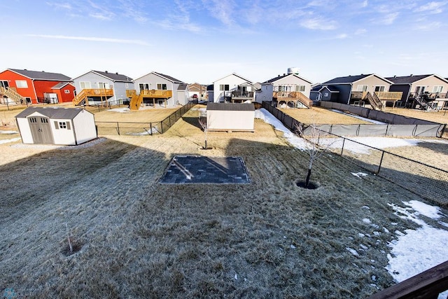 view of yard featuring a residential view, a fenced backyard, an outbuilding, and a storage shed