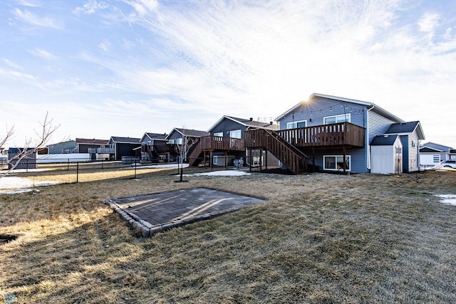 exterior space with a deck, an outbuilding, fence, stairs, and a lawn