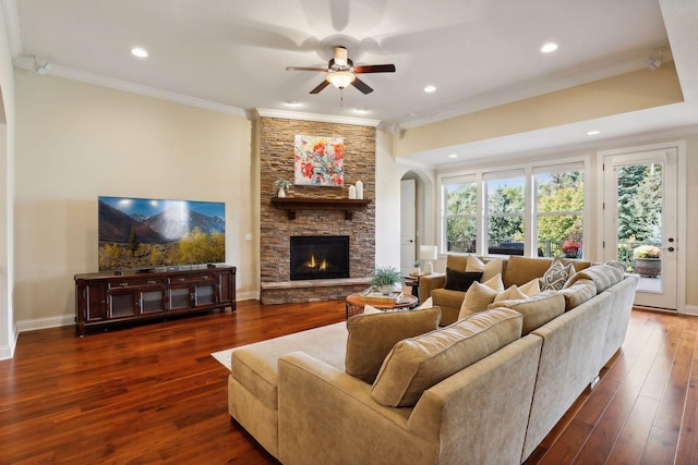 living room featuring crown molding, recessed lighting, a stone fireplace, baseboards, and hardwood / wood-style flooring