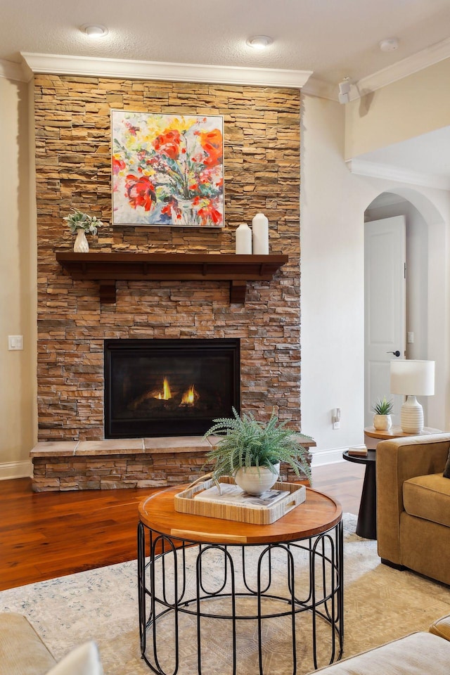 living area with a fireplace, crown molding, and wood finished floors