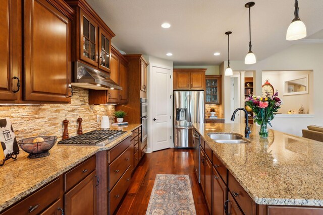 kitchen with under cabinet range hood, stainless steel appliances, dark wood-type flooring, a sink, and decorative backsplash