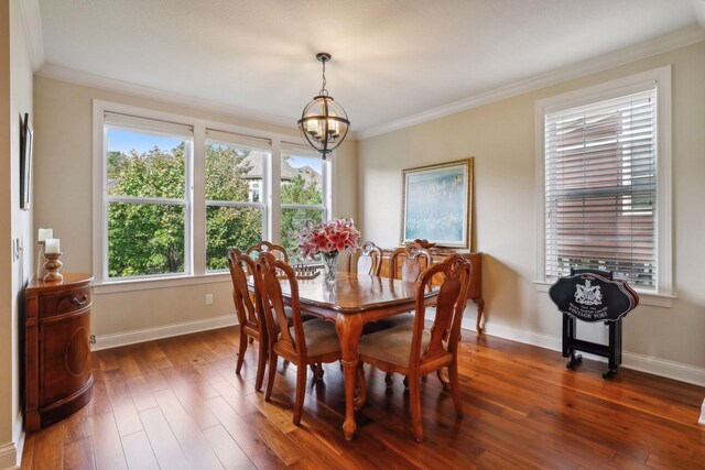 dining area featuring dark wood-style floors, baseboards, ornamental molding, and a chandelier