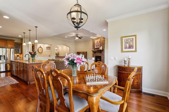 dining space featuring recessed lighting, a large fireplace, baseboards, dark wood finished floors, and crown molding