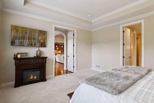 bedroom featuring arched walkways, carpet flooring, visible vents, a tray ceiling, and crown molding