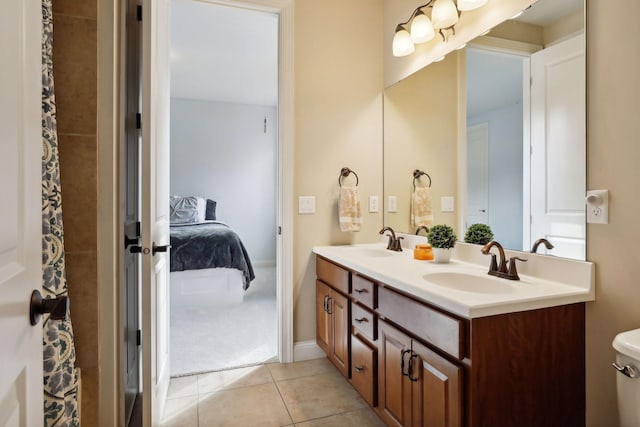 ensuite bathroom with double vanity, tile patterned floors, a sink, and connected bathroom