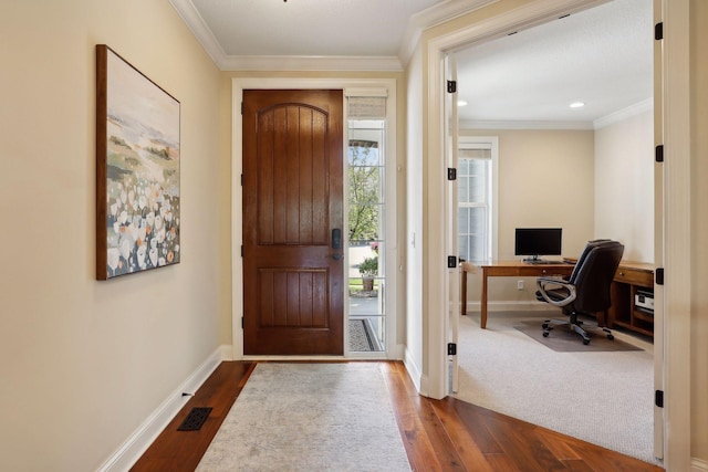 foyer with baseboards, dark wood-style floors, visible vents, and crown molding