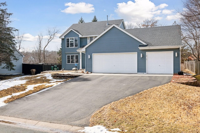 traditional-style house featuring fence, a garage, driveway, and a shingled roof