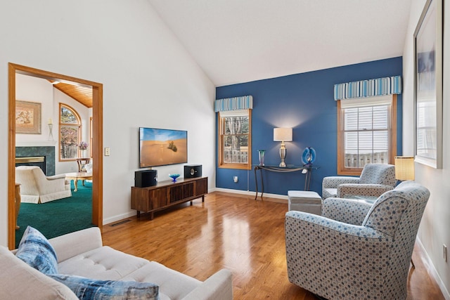 living area with visible vents, baseboards, a fireplace, wood finished floors, and high vaulted ceiling