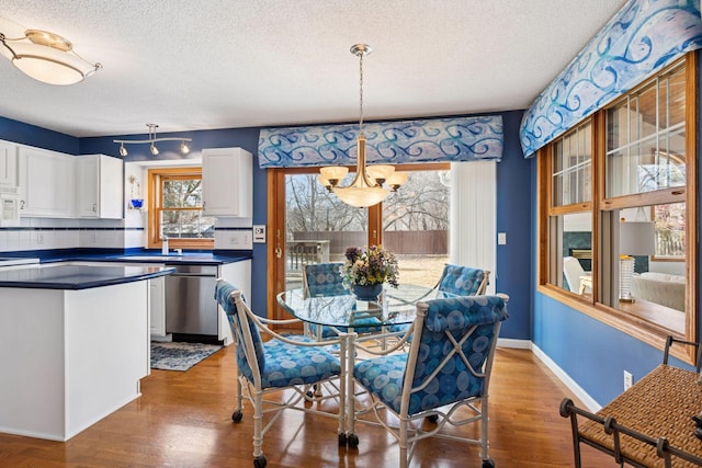 dining area with wood finished floors, baseboards, and a textured ceiling