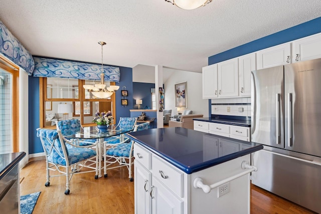 kitchen with dark countertops, white cabinets, light wood-type flooring, and appliances with stainless steel finishes