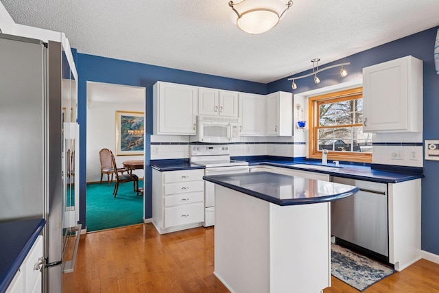 kitchen with dark countertops, white cabinetry, stainless steel appliances, and a sink