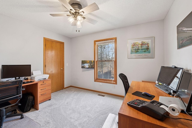 office area featuring visible vents, baseboards, light colored carpet, a textured ceiling, and a ceiling fan