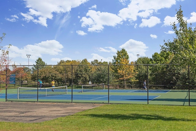 view of tennis court featuring fence and a lawn