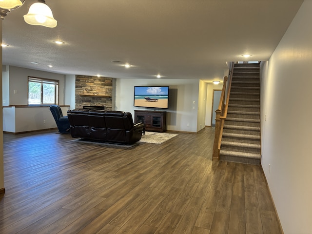 living room featuring baseboards, stairway, dark wood-style flooring, a textured ceiling, and a fireplace