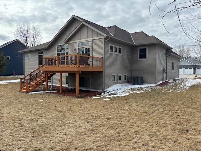 snow covered property featuring a shingled roof, a detached garage, stairway, a wooden deck, and board and batten siding