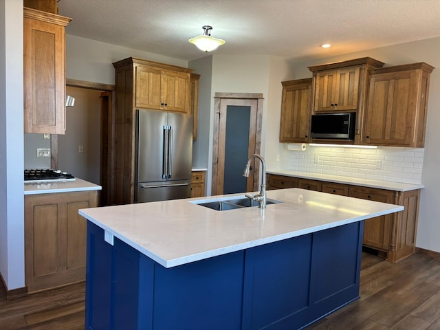 kitchen featuring high end fridge, backsplash, a sink, and dark wood finished floors