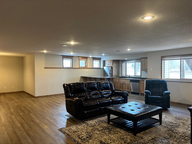 living room featuring dark wood-style floors, recessed lighting, a textured ceiling, and baseboards