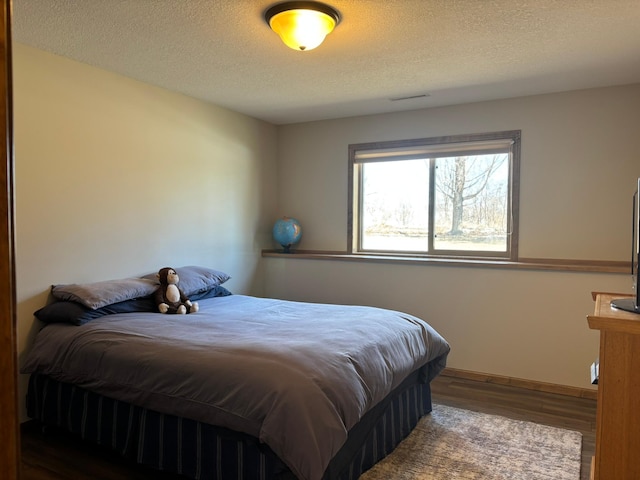 bedroom with a textured ceiling, visible vents, and wood finished floors