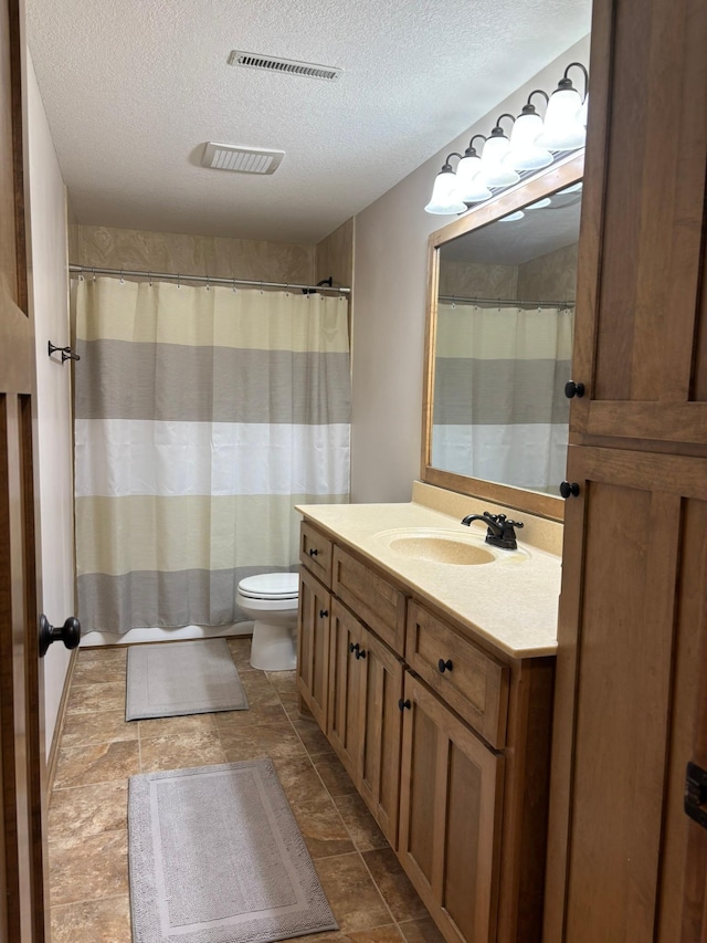 bathroom featuring toilet, visible vents, a textured ceiling, and vanity