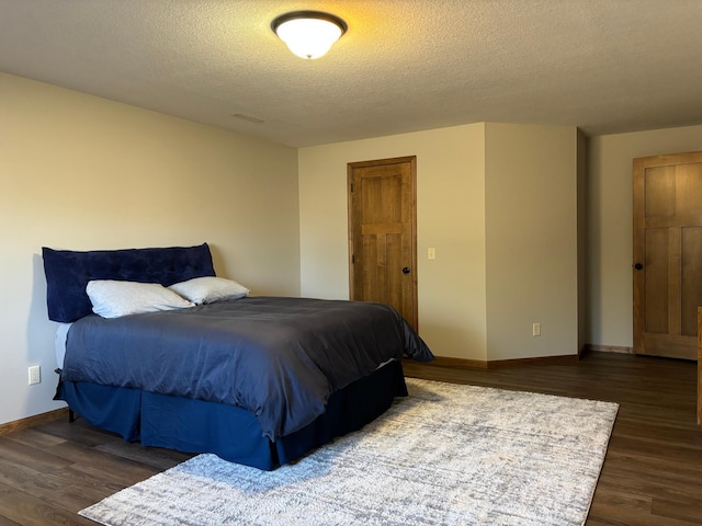 bedroom featuring visible vents, baseboards, dark wood finished floors, and a textured ceiling